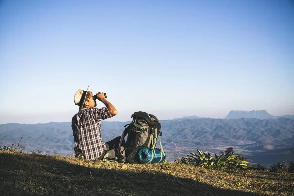 Tourist is watching through binoculars on sunny cloudy sky from